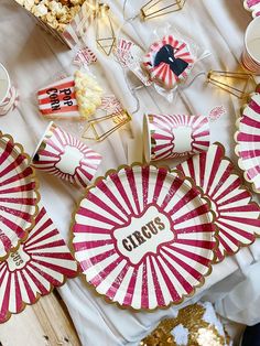 pink and white striped paper plates with gold trimmings on a table filled with candy