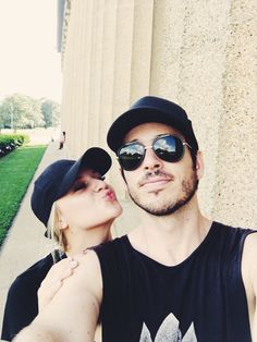 a man and woman standing next to each other in front of a building with columns