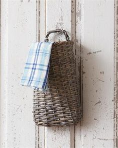 a wicker basket hanging on the side of a white door with a blue checkered towel