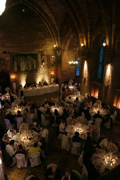 a group of people sitting at tables in a large room with candles on the table