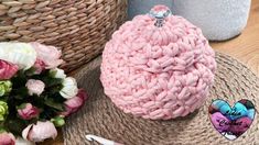 a pink crochet purse sitting on top of a table next to flowers and scissors