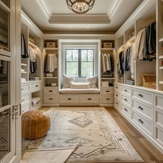 a large walk in closet with lots of white furniture and drawers on either side of the room