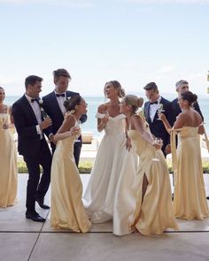 a group of people standing next to each other in formal wear and tuxedos