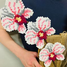 a person holding a piece of art made out of beaded fabric with flowers on it