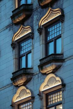 two windows are lit up at night in front of a large building with arched windows