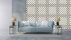 a blue couch sitting in front of a wall with a geometric design on it's side