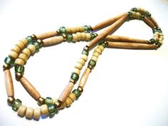 a necklace made out of wooden beads and green glass beads on a white table top