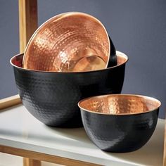 copper and black dishes are sitting on a table