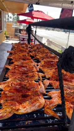 some food is being cooked on a grill with umbrellas and people in the background