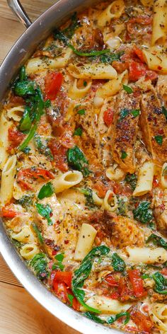 a pan filled with pasta and vegetables on top of a wooden table