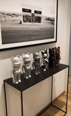 there are many stuffed animals sitting on the shelf in front of the wall and framed photograph