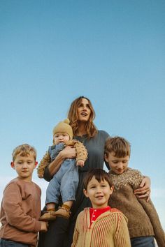 a group of children standing next to each other in front of a blue cloudy sky