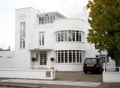 a car parked in front of a large white building with windows and balconies