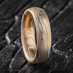 "* Price may vary depending on ring size, please inquire with us directly with your needed size for accurate pricing! This bold and beautiful Mokume Gane ring features our Twist pattern and non oxidized Firestorm metal combination with an etched finish, and low dome profile. The Firestorm palette features 14k yellow gold, 14k red gold, palladium and sterling silver.  Mokume Gane Band Pattern: Twist Palette: Firestorm Width Shown: 5mm Size Shown: 5.5 Finish: Etched  Profile: Low Dome Price does NOT include stones or setting fees. We care about customer service and would like to hear from you! Please contact us to help create your treasured item, we take your concerns and requests to heart and will work together to create your unique designs SPECIAL PRICING FOR SETS. CONTACT US WITH YOUR DES Adjustable Carved Rings For Anniversary, Unique Carved Rings For Wedding, Carved Adjustable Jewelry For Wedding, Japanese Wedding Band, Ceremonial Oxidized Finish Ring, Polymer Clay Mokume Game, Mokume Gane Ring Wedding, Mokume Gane Earrings, Mokume Gane Ring