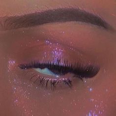 a woman's eye with glitter on it and her lashes in the shape of stars