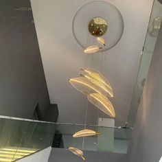 a light fixture hanging from the ceiling in a room with glass railings and stairs