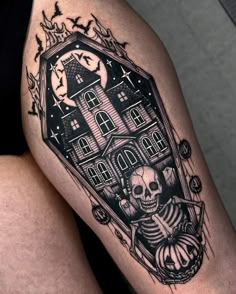 a woman's thigh with a skeleton and house tattoo on it