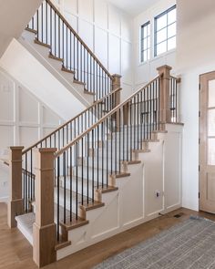 a stair case in a home with hardwood floors and white walls, along with an area rug on the floor