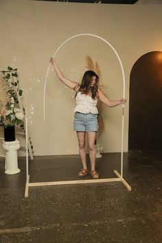 a woman standing in front of a white arch with her arms up and hands out