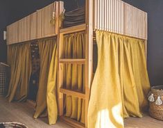 a wooden bunk bed with yellow curtains on the top and bottom, next to a wicker basket