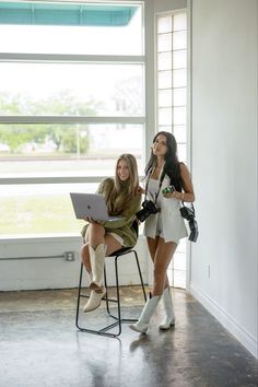 two women sitting in chairs with one on her lap and the other holding a laptop