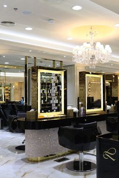 the interior of a hair salon with chandelier and chairs