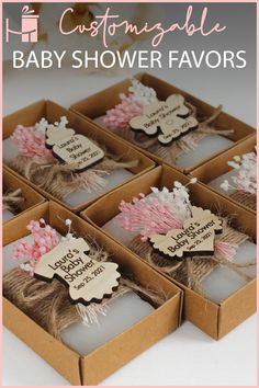 four baby shower favors in small boxes with pink and white flowers on the top one