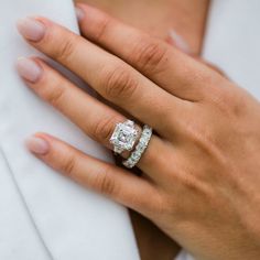 a woman's hand with two wedding rings on her left and the other hand wearing a white shirt