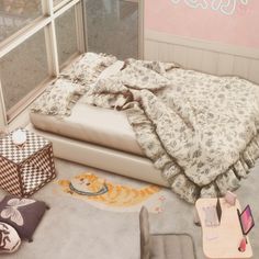 there is a bed with many pillows and blankets on the floor in front of a window