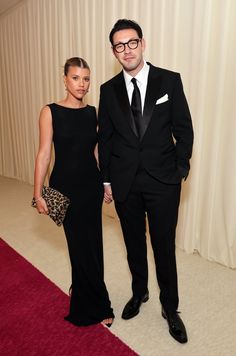 a man and woman in formal wear standing next to each other on a red carpet