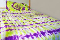 a bed with a purple and green tie - dyed comforter