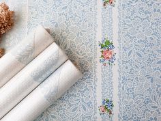 three rolls of toilet paper sitting on top of a blue and white table cloth next to a teddy bear