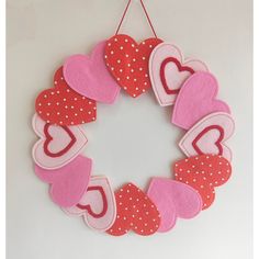 a wreath made out of felt with hearts hanging from the front and back sides on a white wall