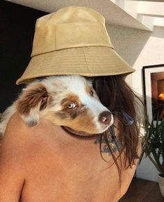 a woman wearing a hat with a dog on her shoulders and the back of her head