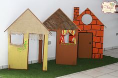 three cardboard houses made to look like they are in the grass