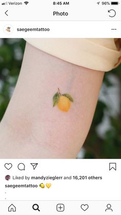 an orange on the side of a woman's arm with a small green leaf on it