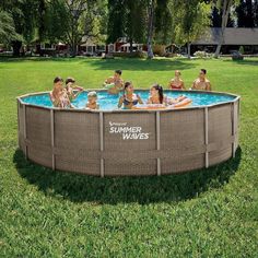 a group of people sitting around a swimming pool in the middle of a field with grass