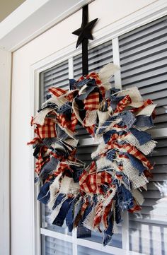 a patriotic wreath is hanging on the front door with an arrow above it and red white and blue plaid fabric