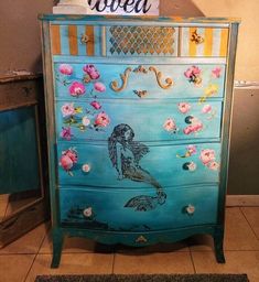 a blue dresser with flowers painted on it