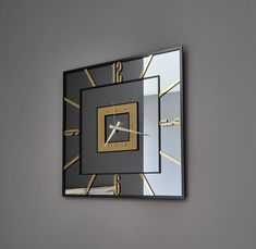 a square clock mounted to the wall with gold accents