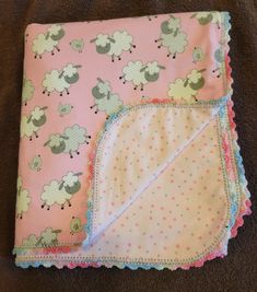 two baby blankets laying on top of each other next to a brown blanket with pink and green sheep