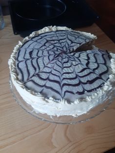 a cake sitting on top of a wooden table next to a pan with a knife in it