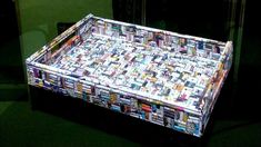 a large tray made out of magazines on top of a green table with black walls