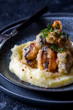 a plate with mashed potatoes and fried shrimp on top, garnished with parsley