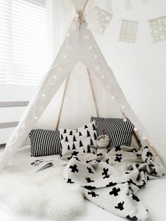 a teepee tent with lights and pillows on the floor