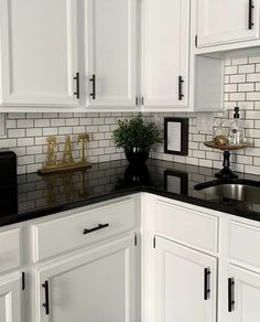 a kitchen with white cabinets and black counter tops