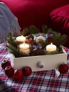 a wooden box filled with candles on top of a plaid table cloth covered tablecloth