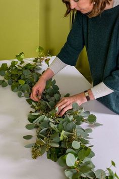 a woman is arranging greenery on a table