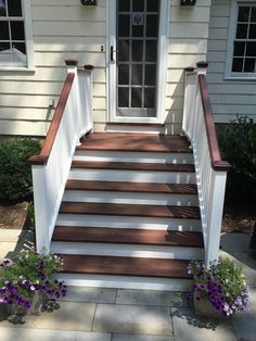 the steps leading up to the front door are made of wood and have white railings