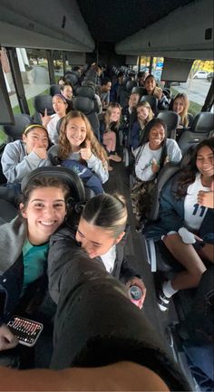 a large group of people sitting in the back of a bus with their thumbs up